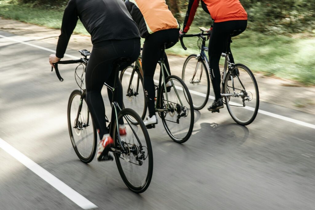 Group of cyclists riding on an outdoor path in bright sunlight, showcasing teamwork and fitness.